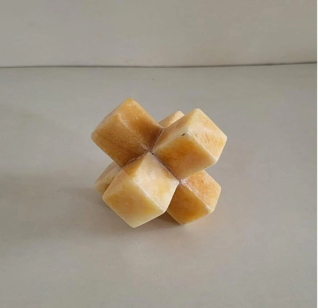 A decorative geometric stone jack sculpture in warm amber tones