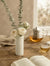 White fluted marble Vase standing on a rustic wooden table with a minimalist, warm home decor setting.