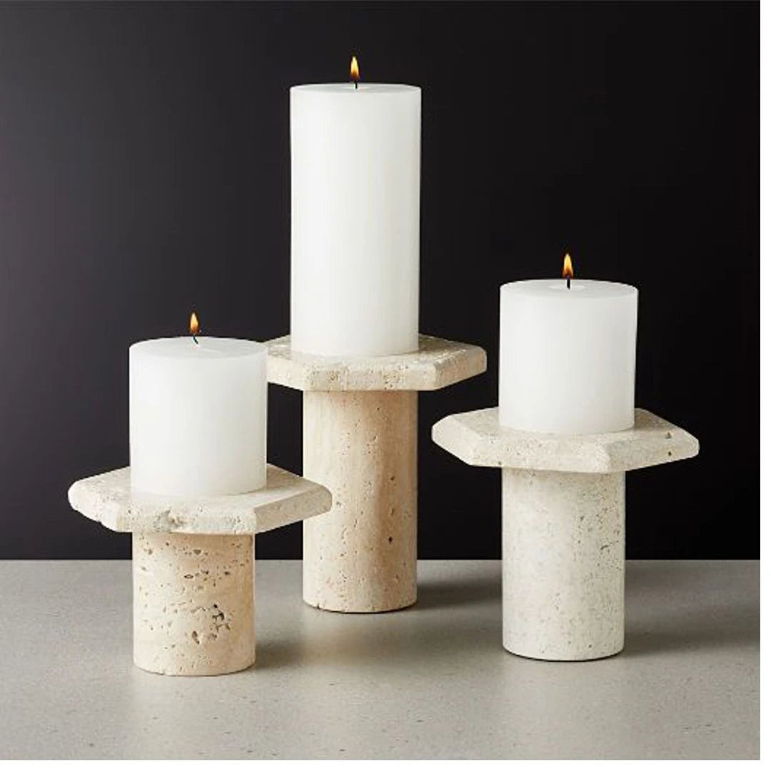Handcrafted beige travertine marble candle holders in varying heights, styled with pillar candles for a calm, neutral luxury interior.