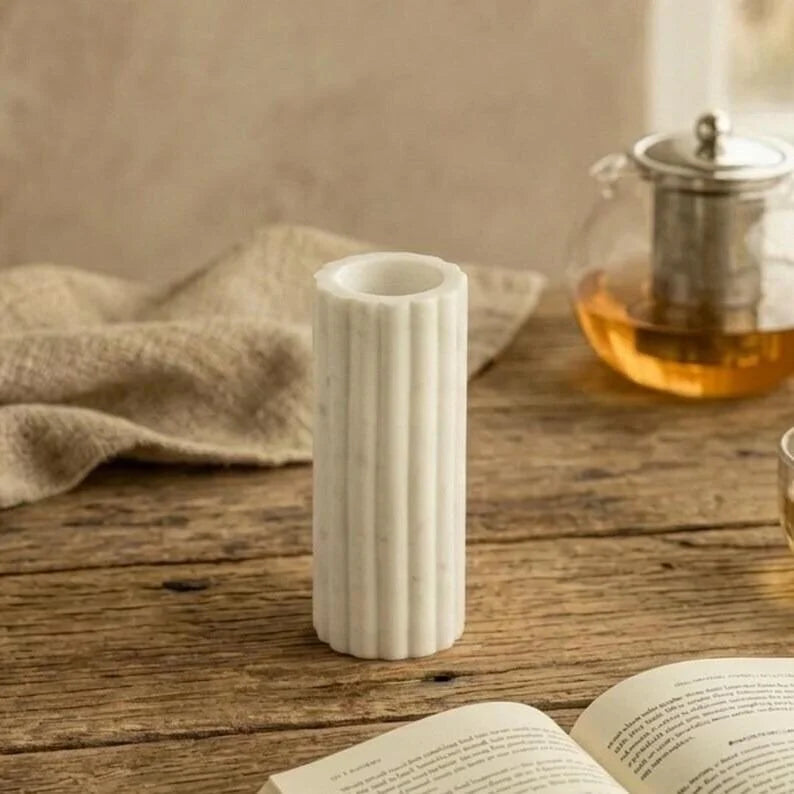 Handmade white marble vase with vertical fluted design styled in a neutral, modern interior.